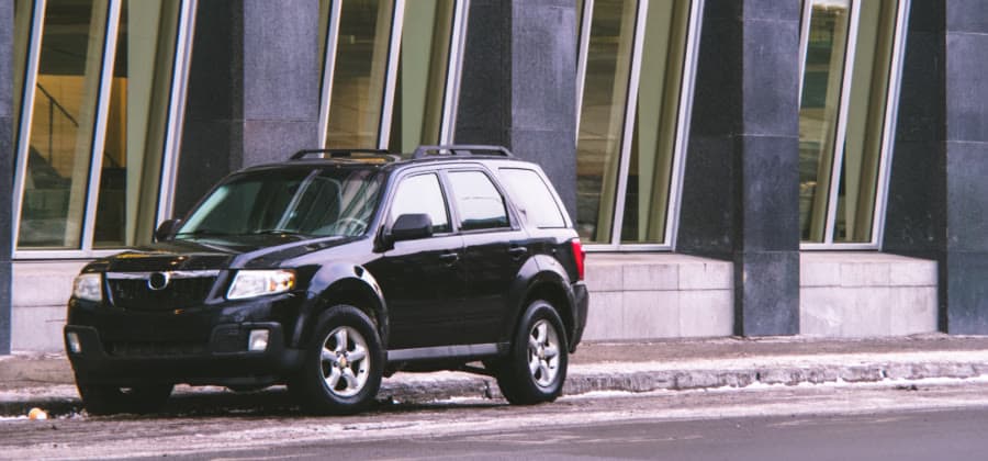 A black SUV parked outside a glass-fronted building